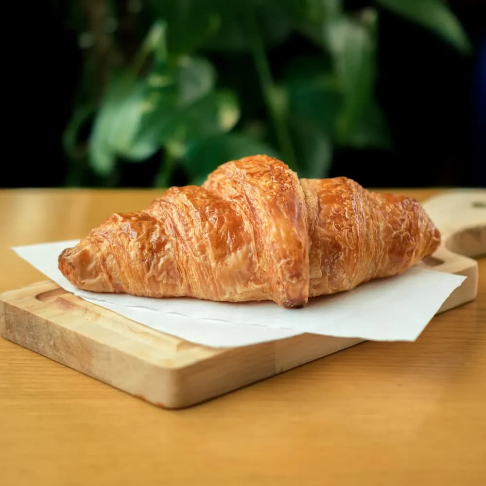 Golden butter croissant on parchment paper on a wooden board