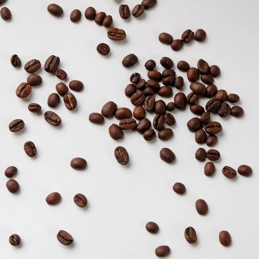 Light roast whole coffee beans scattered on a white surface