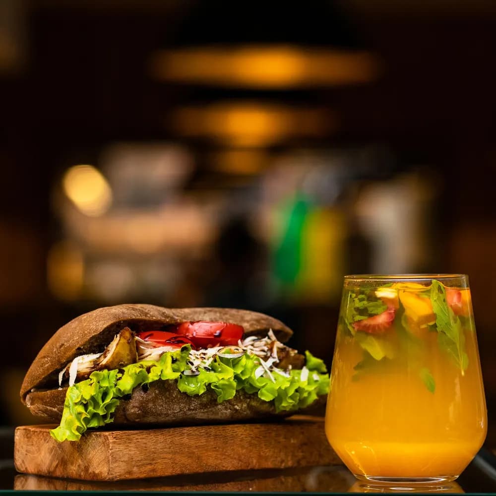 Veggie sandwich with lettuce and tomato on a rustic roll on a wooden board