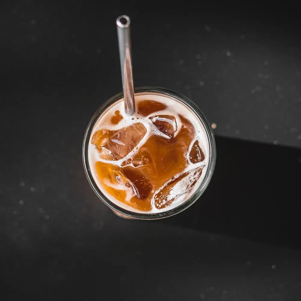Glass of iced cold brew coffee with ice cubes and a metal straw